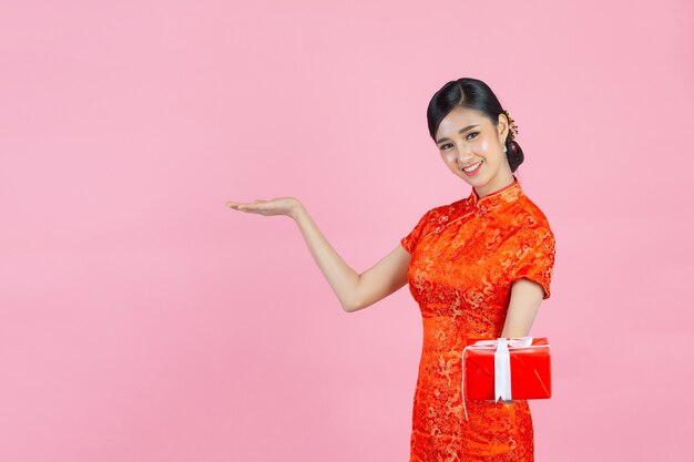 Sonrisa feliz hermosa mujer asiática y caja de regalo de celebración en año nuevo chino sobre fondo rosa.