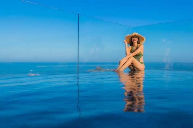 Foto gratuita sonrisa feliz de hermosas mujeres asiáticas jóvenes relajarse alrededor de la piscina al aire libre en el complejo hotelero para viajar en vacaciones