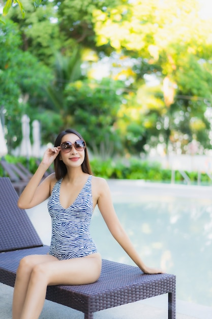 Sonrisa feliz de hermosas mujeres asiáticas jóvenes relajarse alrededor de la piscina al aire libre en el hotel resort