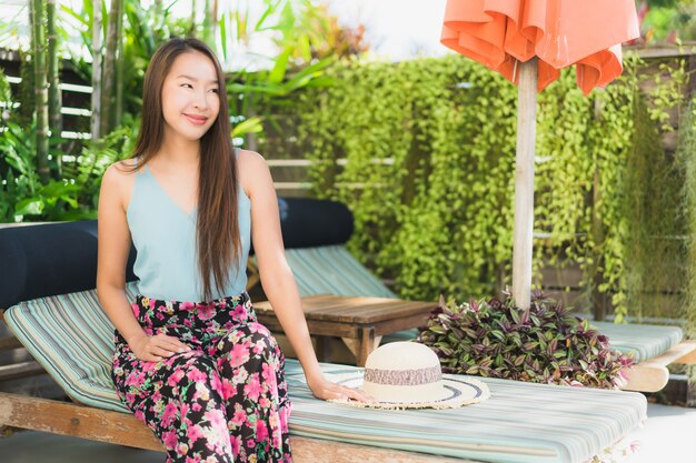 La sonrisa feliz de la mujer asiática joven hermosa y se relaja en piscina