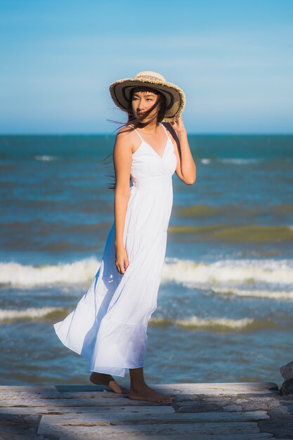 La sonrisa feliz de la mujer asiática joven hermosa del retrato se relaja alrededor de la playa y del mar neary