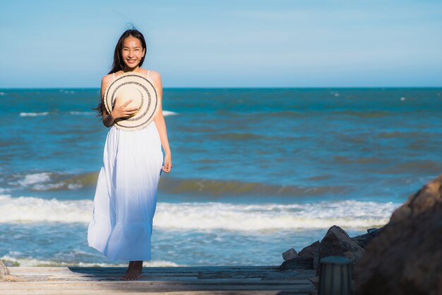 La sonrisa feliz de la mujer asiática joven hermosa del retrato se relaja alrededor de la playa y del mar neary