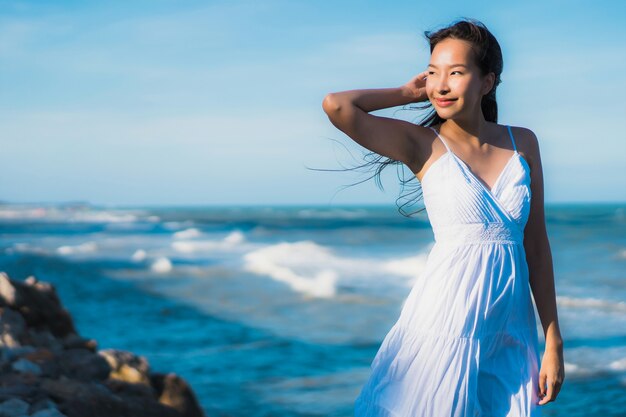 La sonrisa feliz de la mujer asiática joven hermosa del retrato se relaja alrededor de la playa y del mar neary