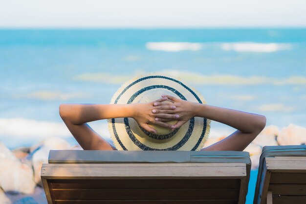 La sonrisa feliz de la mujer asiática joven hermosa del retrato se relaja alrededor de la playa y del mar neary