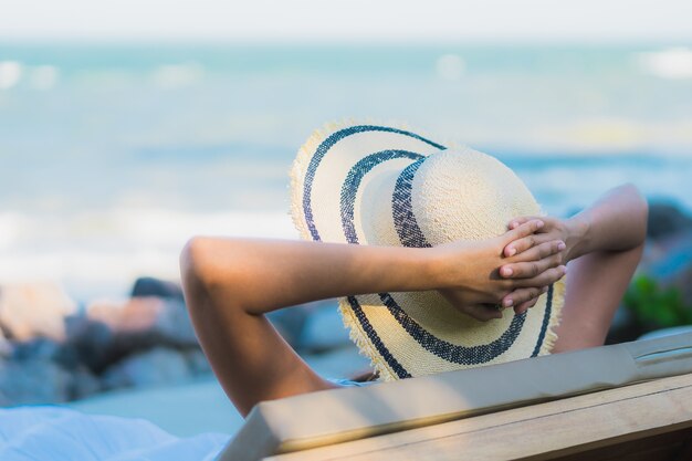 La sonrisa feliz de la mujer asiática joven hermosa del retrato se relaja alrededor de la playa y del mar neary