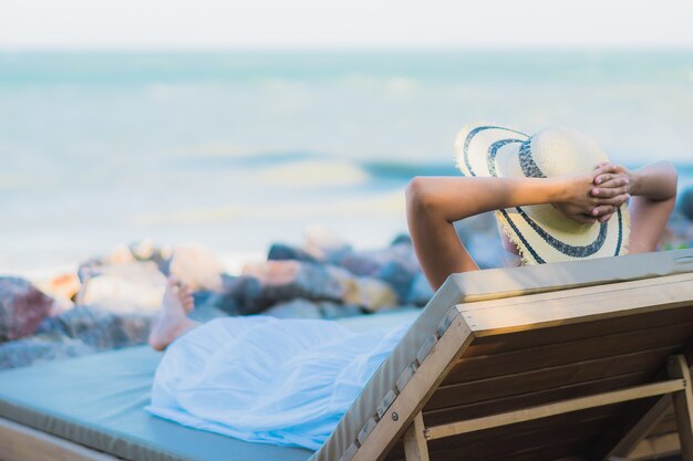 La sonrisa feliz de la mujer asiática joven hermosa del retrato se relaja alrededor de la playa y del mar neary