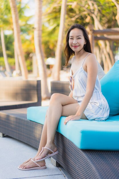 La sonrisa feliz de la mujer asiática joven hermosa del retrato se relaja alrededor de la playa y del mar neary