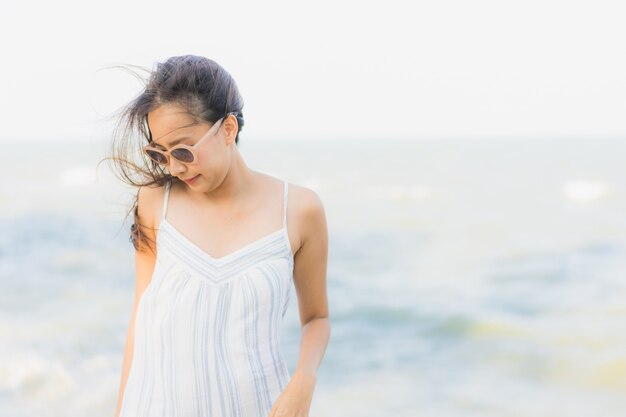 La sonrisa feliz de la mujer asiática joven hermosa del retrato se relaja alrededor de la playa y del mar neary