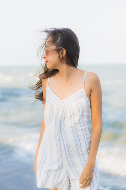 La sonrisa feliz de la mujer asiática joven hermosa del retrato se relaja alrededor de la playa y del mar neary