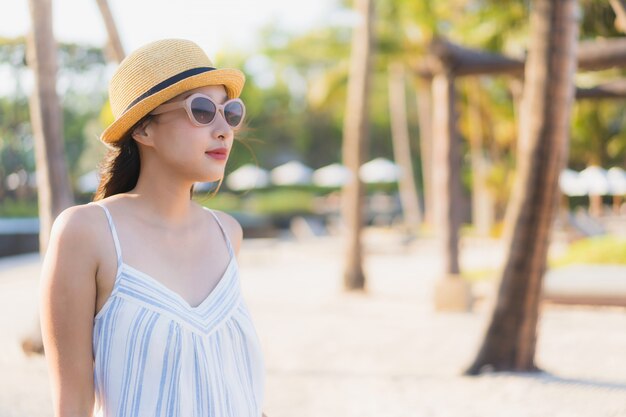 La sonrisa feliz de la mujer asiática joven hermosa del retrato se relaja alrededor de la playa y del mar neary