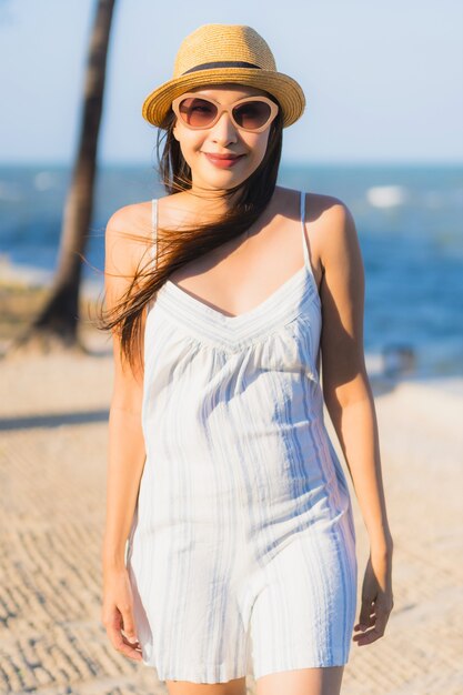 La sonrisa feliz de la mujer asiática joven hermosa del retrato se relaja alrededor de la playa y del mar neary