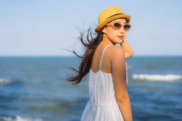 La sonrisa feliz de la mujer asiática joven hermosa del retrato se relaja alrededor de la playa y del mar neary