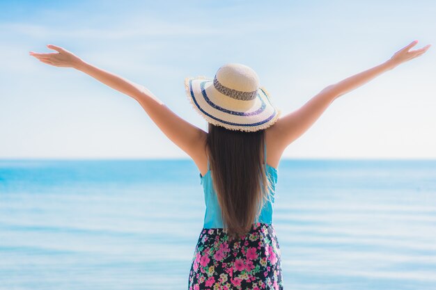 La sonrisa feliz de la mujer asiática joven hermosa del retrato se relaja alrededor de la playa océano y mar