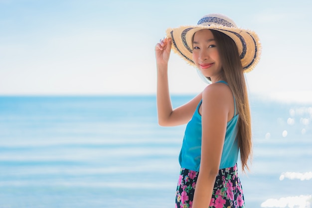 La sonrisa feliz de la mujer asiática joven hermosa del retrato se relaja alrededor de la playa océano y mar
