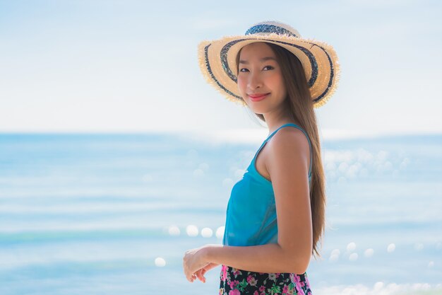 La sonrisa feliz de la mujer asiática joven hermosa del retrato se relaja alrededor de la playa océano y mar