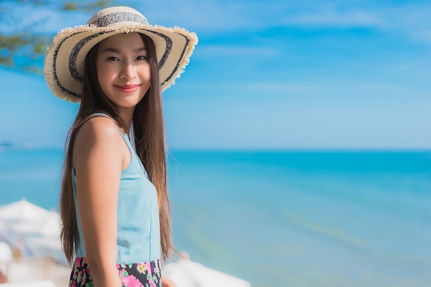 La sonrisa feliz de la mujer asiática joven hermosa del retrato se relaja alrededor de la playa océano y mar