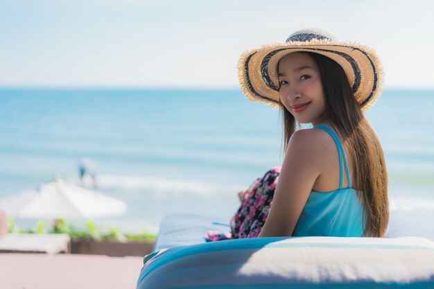 La sonrisa feliz de la mujer asiática joven hermosa del retrato se relaja alrededor de la playa océano y mar