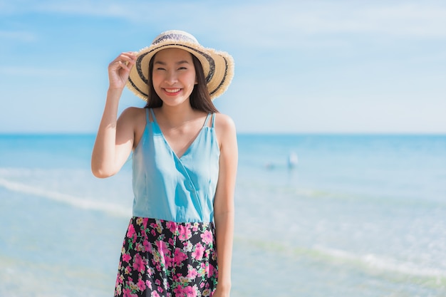 La sonrisa feliz de la mujer asiática joven hermosa del retrato se relaja alrededor de la playa océano y mar