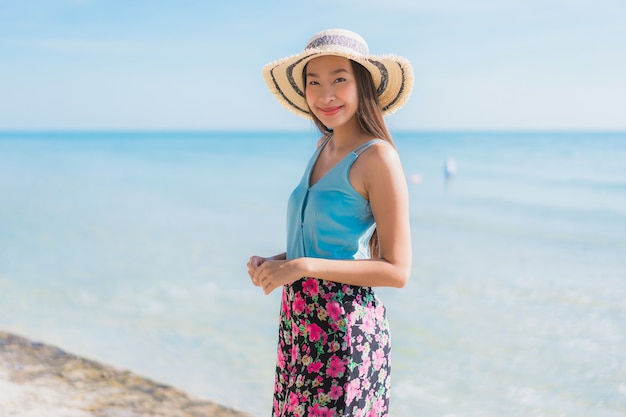 La sonrisa feliz de la mujer asiática joven hermosa del retrato se relaja alrededor de la playa océano y mar