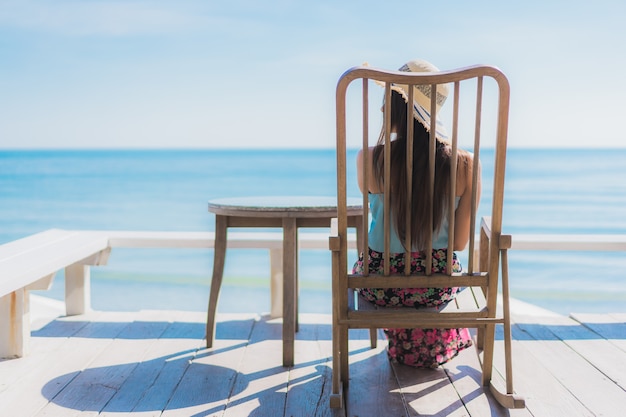 La sonrisa feliz de la mujer asiática joven hermosa del retrato se relaja alrededor de la playa océano y mar