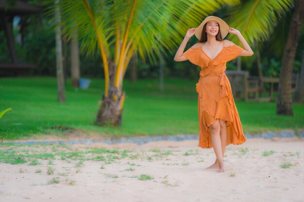 La sonrisa feliz de la mujer asiática joven hermosa del retrato se relaja en el océano del mar de la playa