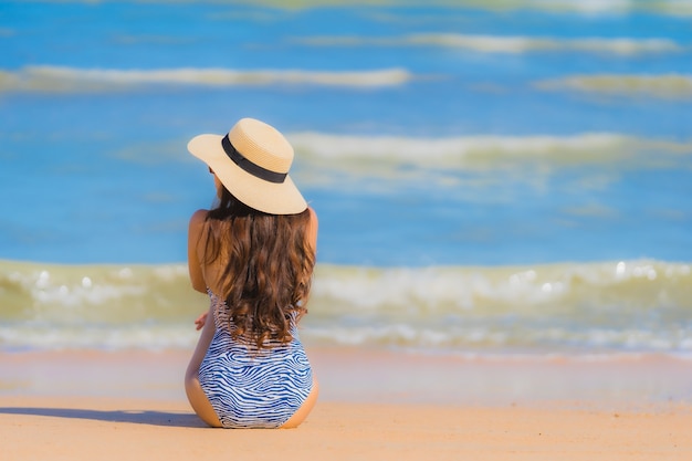 La sonrisa feliz de la mujer asiática joven hermosa del retrato se relaja en el océano tropical del mar de la playa para el viaje del ocio