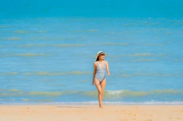 La sonrisa feliz de la mujer asiática joven hermosa del retrato se relaja en el océano tropical del mar de la playa para el viaje del ocio