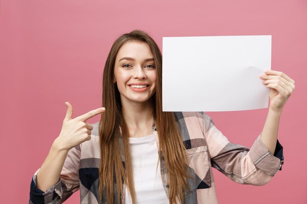 Sonrisa joven mujer de pie señalando con el dedo a un tablero en blanco