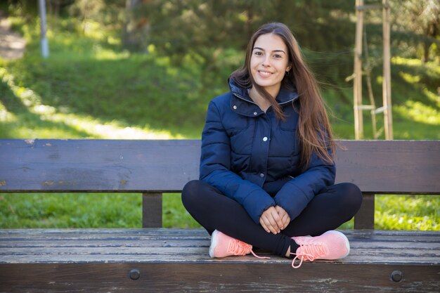 Sonrisa mujer bastante deportiva que presenta en la cámara en banco