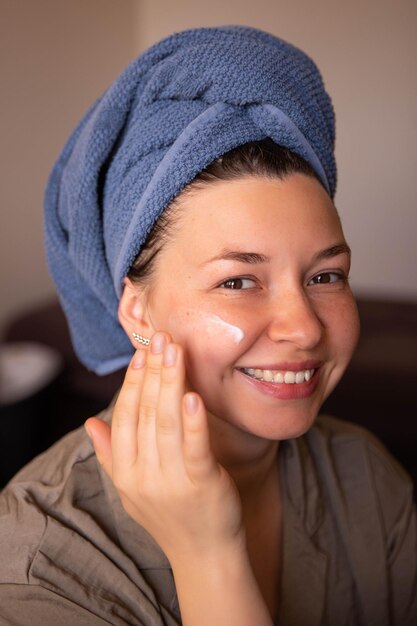 Sonrisa de mujer con crema para la cara mira a la cámara