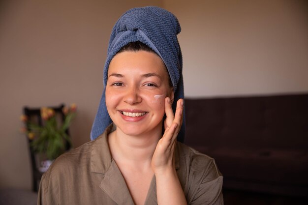 Sonrisa mujer mira el espejo con crema para la cara vista de cerca