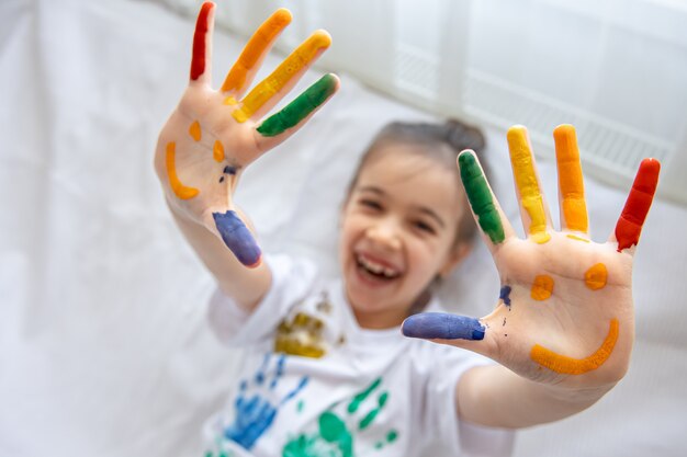 Sonrisas pintadas en las palmas de una niña. Divertidos dibujos brillantes en las palmas de los niños.