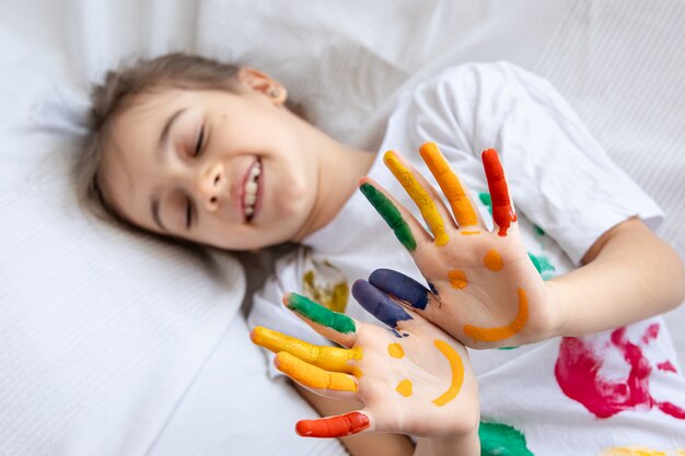 Sonrisas pintadas en las palmas de una niña. Divertidos dibujos brillantes en las palmas de los niños.