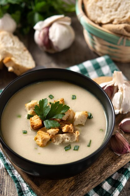 Sopa de ajo cubierta con picatostes en un tazón sobre una mesa de madera