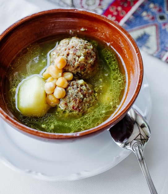 sopa de albóndigas en caldo con papas, frijoles y hierbas.