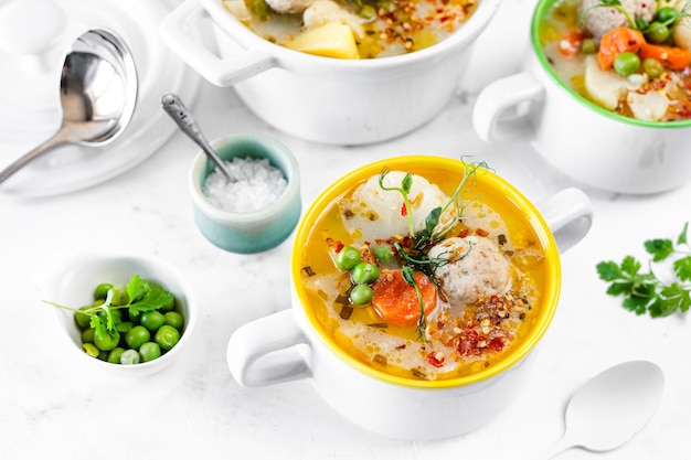 Sopa con albóndigas coliflor guisantes zanahorias y crema sobre un fondo blanco Enfoque selectivo