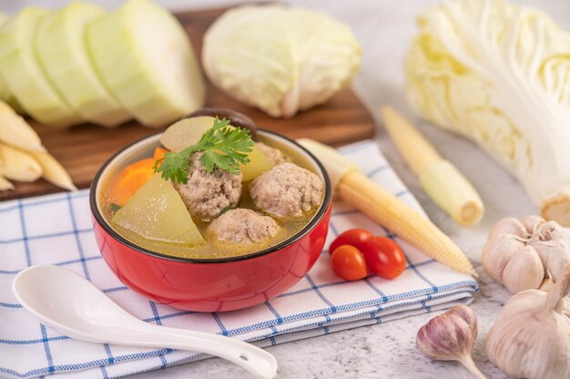 Sopa de bolas de cerdo en una taza sobre un paño blanco azulado.