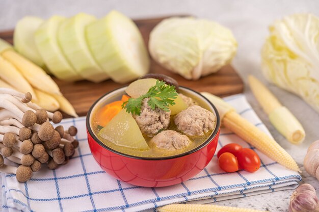 Sopa de bolas de cerdo en una taza sobre un paño blanco azulado.