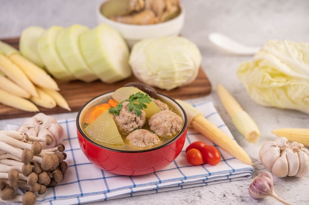 Sopa de bolas de cerdo en una taza sobre un paño blanco azulado.