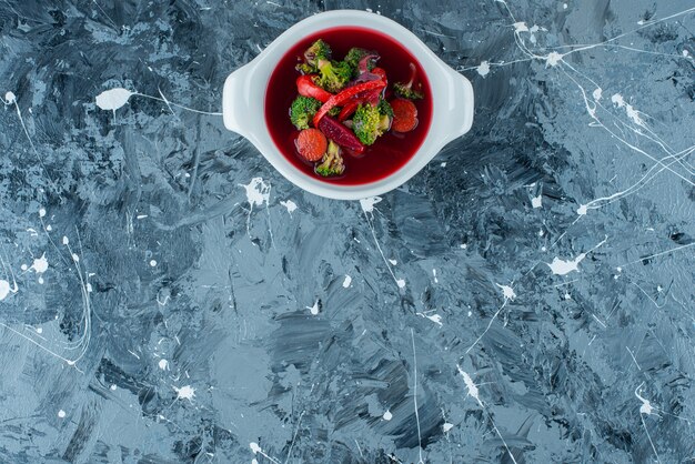 Sopa de borsch casera en un cuenco, sobre el fondo azul.