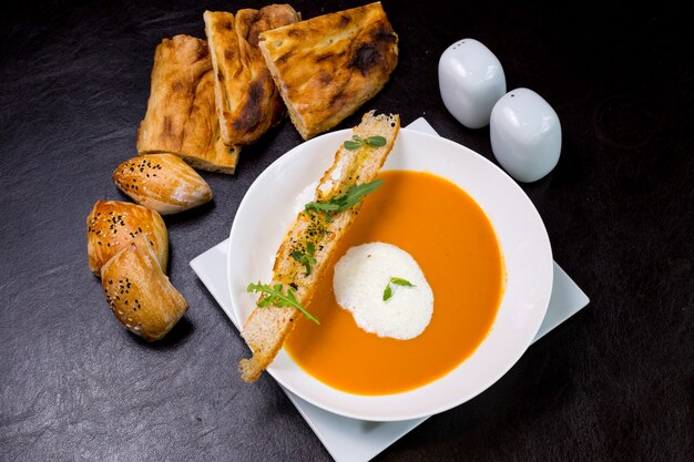 Sopa de calabaza con bollos de espuma de leche galletas de rúcula vista superior