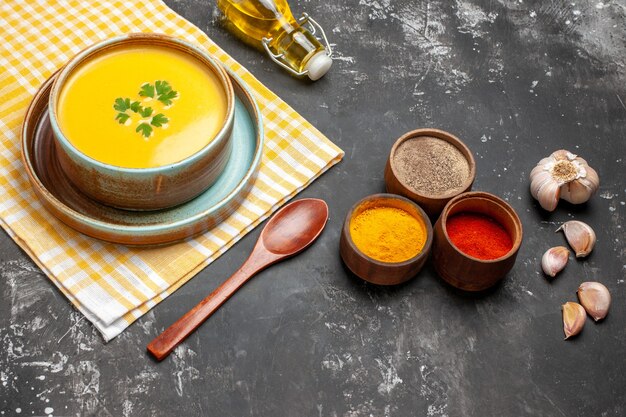 Sopa de calabaza vista frontal con ajo y aceite sobre una mesa oscura