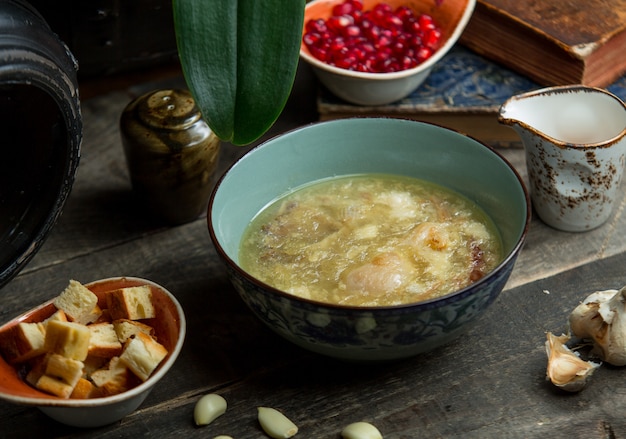 Sopa de caldo de pollo saludable servido con galletas de pan.