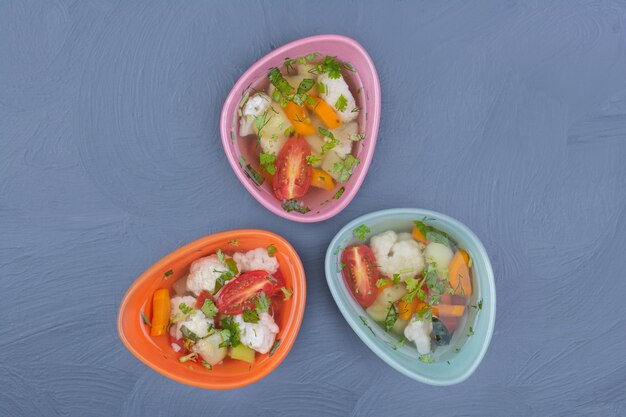 Foto gratuita sopa de caldo en tazas multicolores con verduras picadas