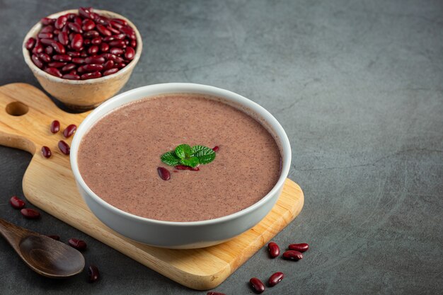 Sopa caliente de frijoles rojos en un tazón blanco sobre una tabla para cortar