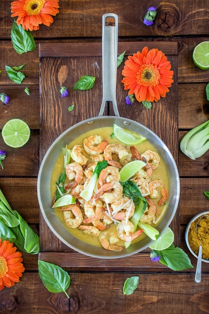 Sopa de camarones al curry servida en una olla de plata sobre una mesa marrón