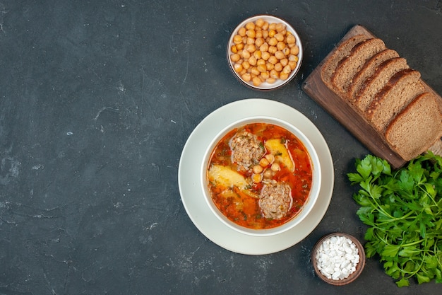 Sopa de carne vista superior con hogazas de pan sobre un fondo gris oscuro