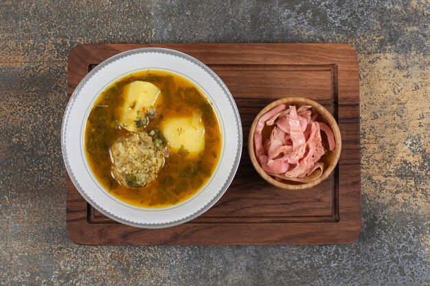 Sopa casera con albóndigas sobre tabla de madera.