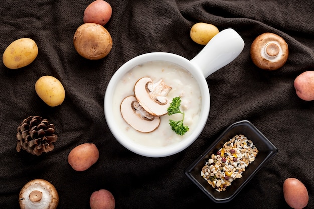 Sopa de champiñones en un frasco blanco con champiñones sobre un paño negro