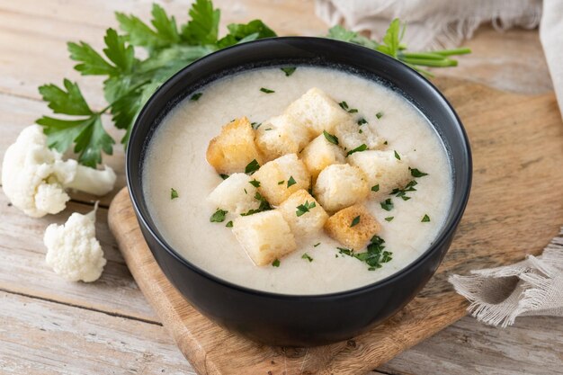 Sopa de coliflor en un bol sobre una mesa de madera